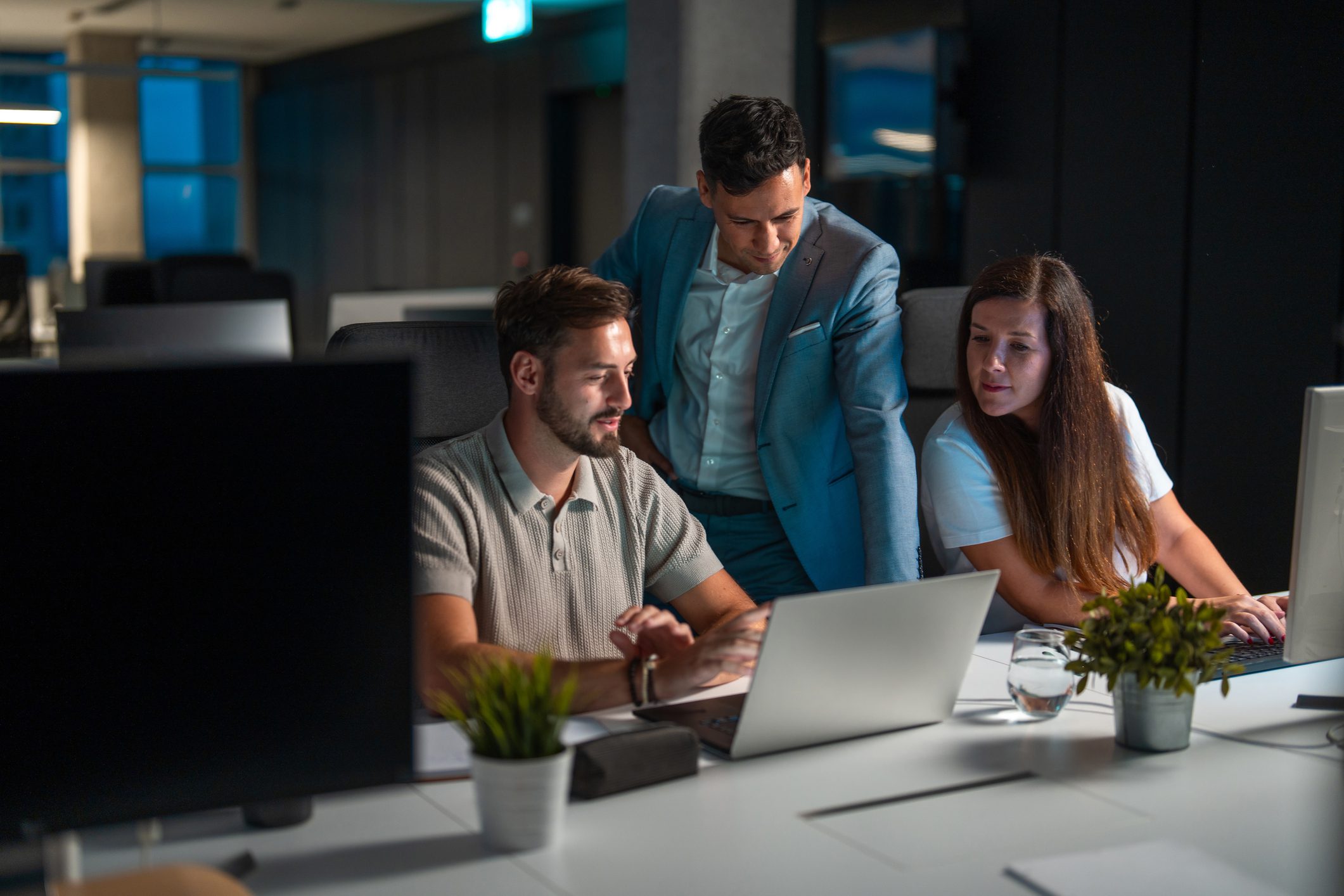 Colleagues discussing work on laptops